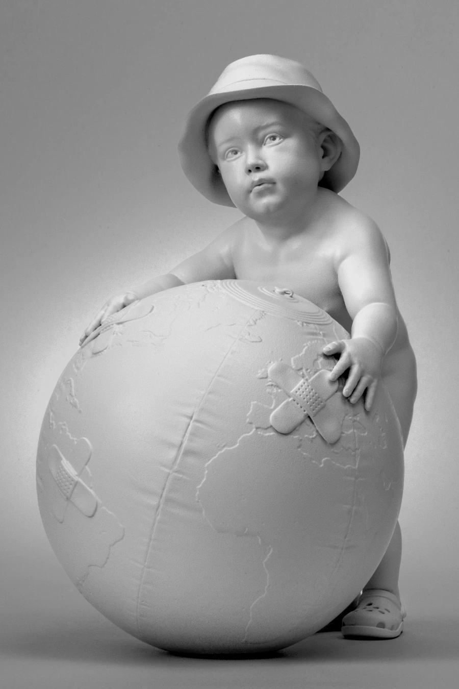 Fixed, 2024 Fixed, 2024. Monochrome sculpture of a child holding a bandaged globe.