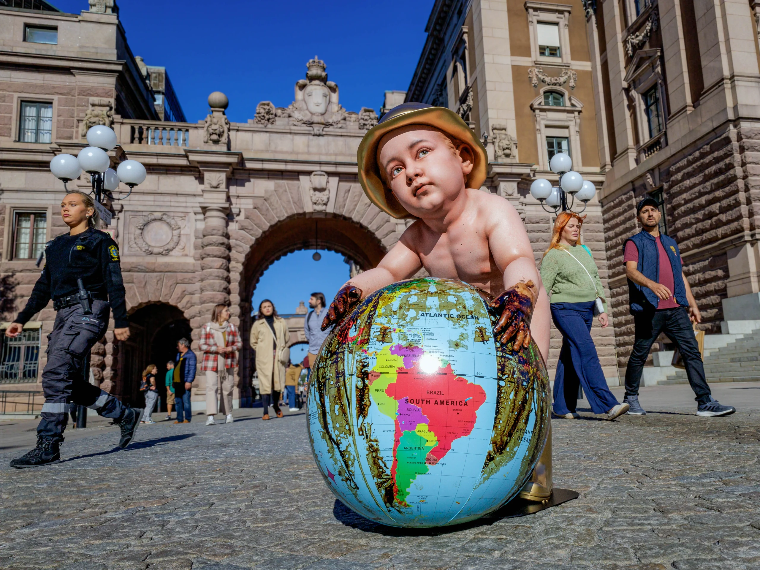 End of the Game by Daniel Paul, child leaning on an oil-stained globe outside the Swedish Parliament in Stockholm