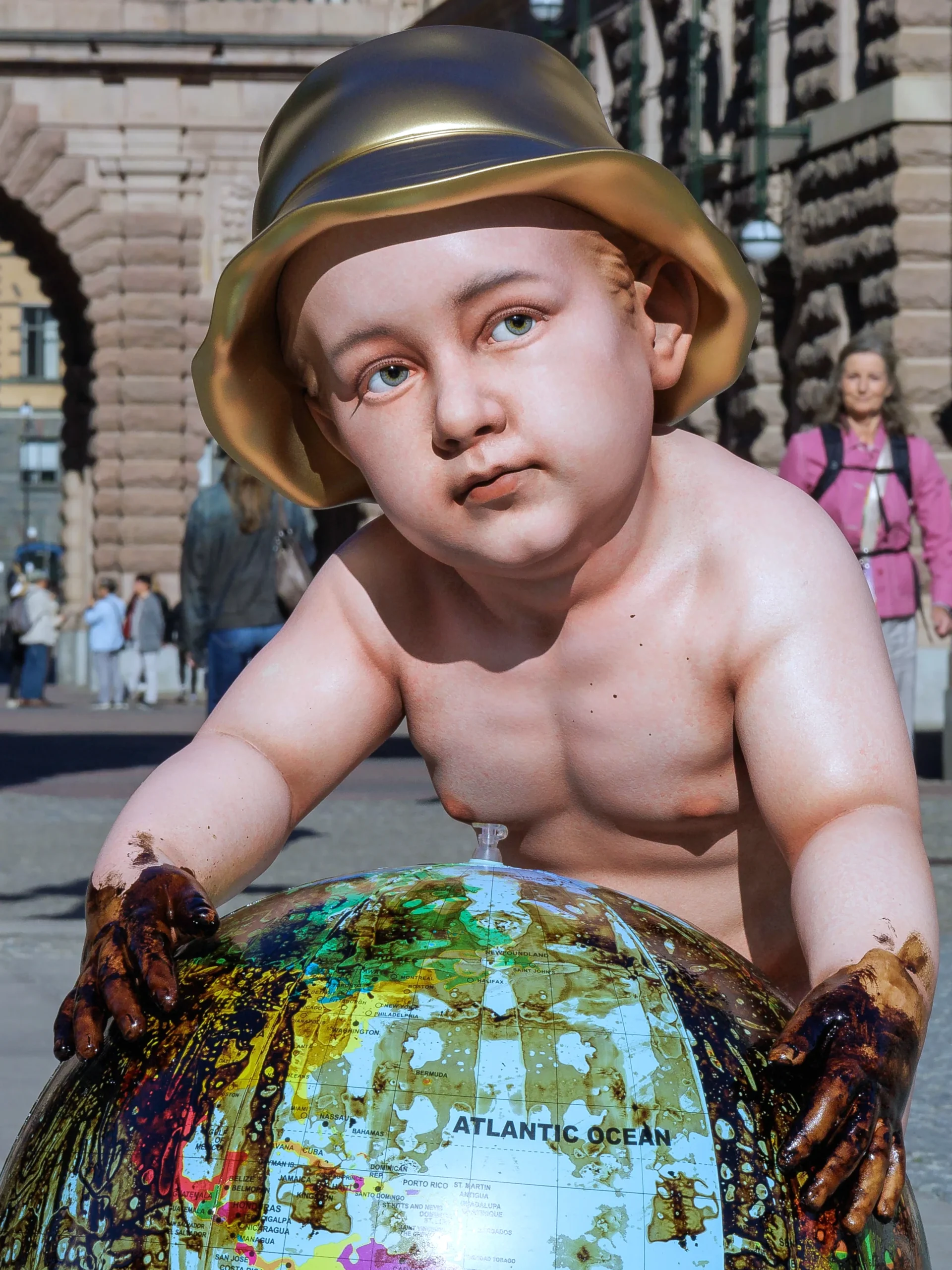 Front detail of Daniel Paul’s End of the Game sculpture showing a child with oil-stained hands leaning on a globe